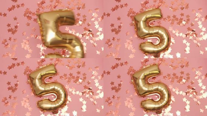 Golden balloons in the shape of five falls on pink