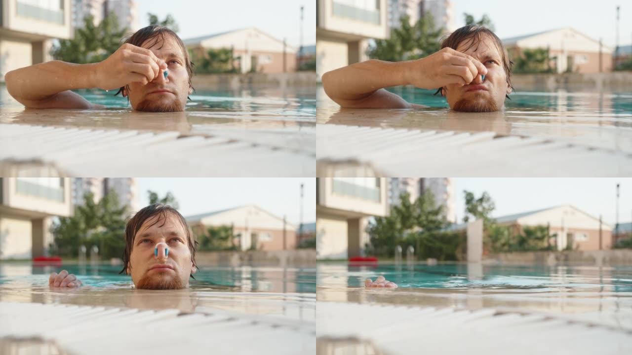 游泳池里的一个人戴上蓝色鼻子的衣夹，然后在水下。鼻毛。夏天和外面的阳光
