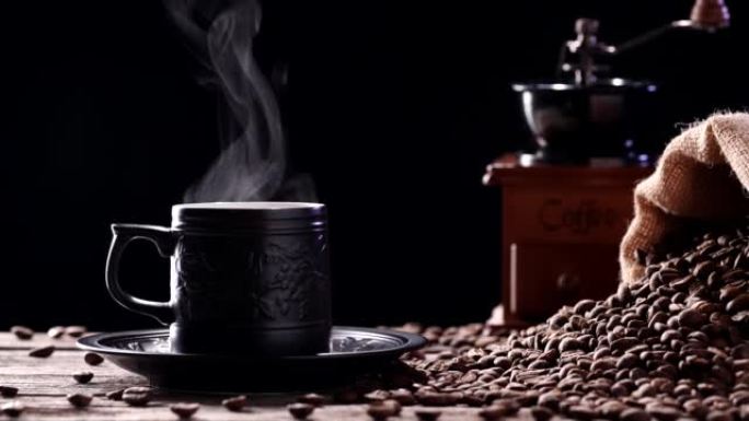 杯子里有天然咖啡烟雾的热饮料。一个热咖啡杯的特写镜头，自然蒸汽上升，黑色背景下的古董研磨机，4k。餐