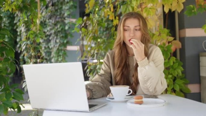 女孩用咖啡吃甜食，并在笔记本电脑上工作