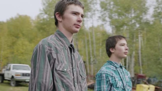 在美国科罗拉多州的一个小镇家族牧场上，两个年轻的牧场主男孩站在一起，从相机上移开的视频肖像
