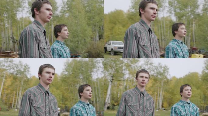 在美国科罗拉多州的一个小镇家族牧场上，两个年轻的牧场主男孩站在一起，从相机上移开的视频肖像