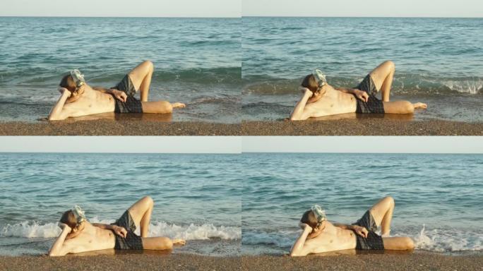 一个戴着潜水面具的人躺在海边，海浪。