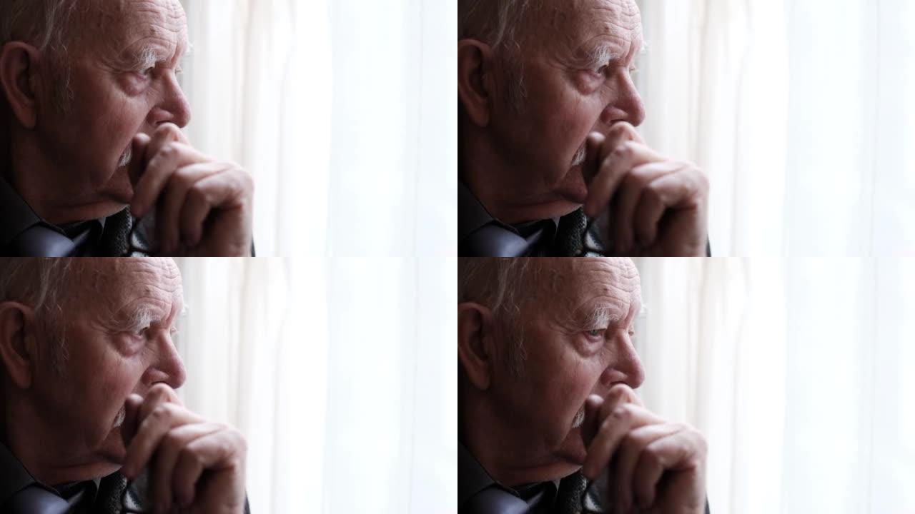 窗户旁沮丧的祖父肖像，特写一位沮丧的老人的肖像