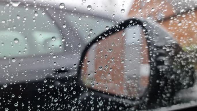 雨滴从靠近后视镜的车窗上流下。