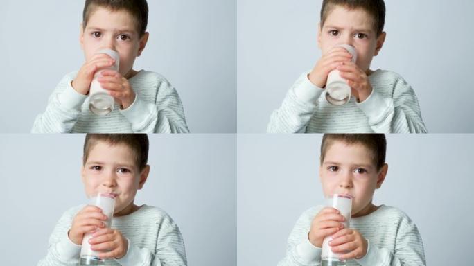 一个可爱的5岁男孩喝开菲尔或牛奶酸奶，并在白色背景下微笑。