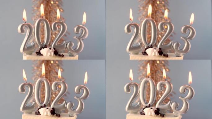 快乐新2023年数字蜡烛红蓝背景杉树圣诞装饰背景。女性手工点燃蜡烛配火柴，蛋糕切片寒假