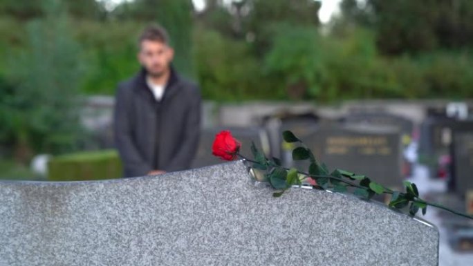 男人把玫瑰放在坟墓上