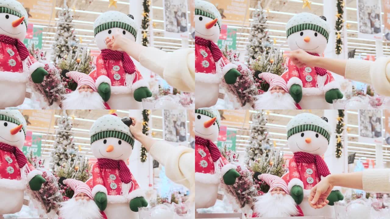 女孩在购物中心检查并触摸圣诞雪人。商场里的圣诞市场