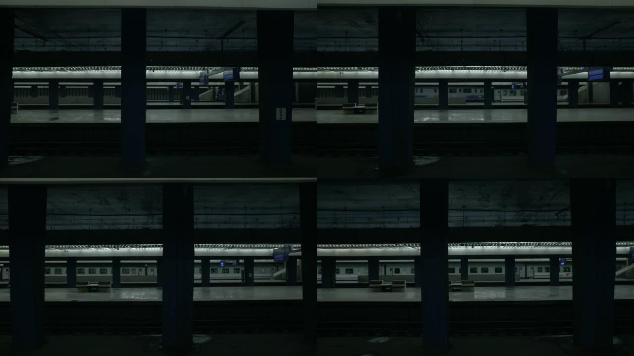 火车经过一个空的火车站。平台上没有人。火车站的柱子和昏暗的灯光。