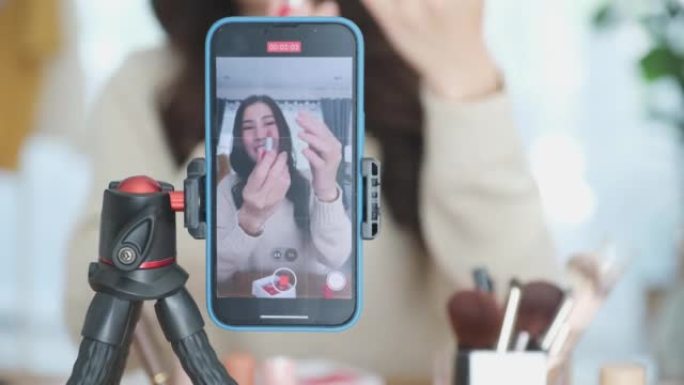 年轻的亚洲女性美容化妆艺术家vlogger，博客作者录制化妆教程，通过智能手机在网站和社交媒体上分享