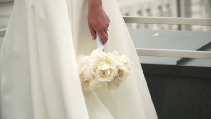 新娘拿着白色花束的特写镜头。
