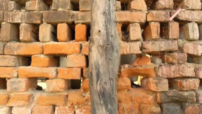 印度老人以旧砖墙为背景，砖墙纹理，结构。旧碎砖，水泥接缝，特写