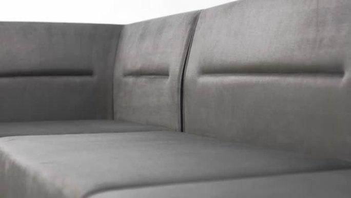 白色背景上由灰色纺织品制成的转角沙发柔软舒适的靠垫。