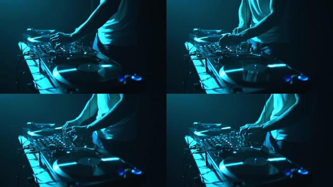 锐舞派对DJ在舞台上混合黑胶唱片。唱片骑师在黑暗之夜俱乐部演奏音乐