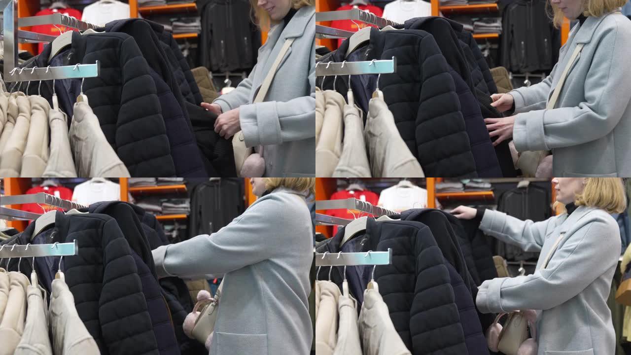 穿着蓝色外套的女人在商店里选择一件男式夹克。
