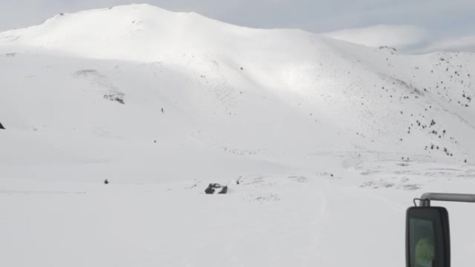 雪猫ratrack用扫雪机准备滑雪场，驶过滑雪胜地的深雪道。重型机械运输山峰上的自由式滑雪者