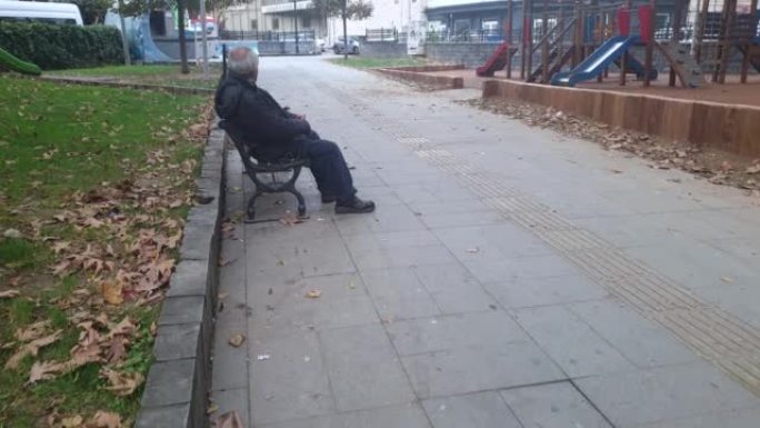 坐在城市公园里的皱巴巴的老人