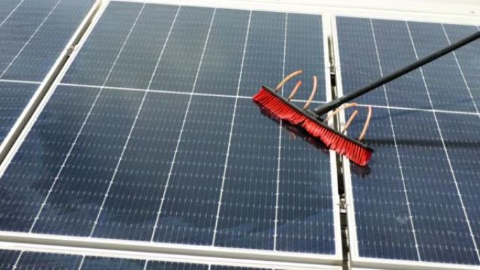 工人用刷子和水清洁太阳能电池板。清洁和绿色替代能源概念。