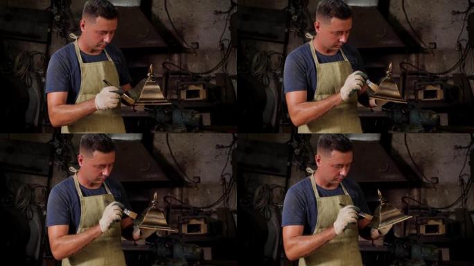 一个铁匠用金粉在锻造中画金属钟的特写镜头。
