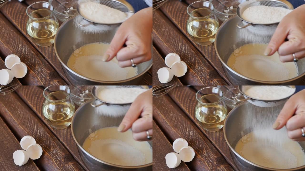 妇女的手通过金属筛筛优质小麦粉，同时为纸杯蛋糕或其他零食准备面团。