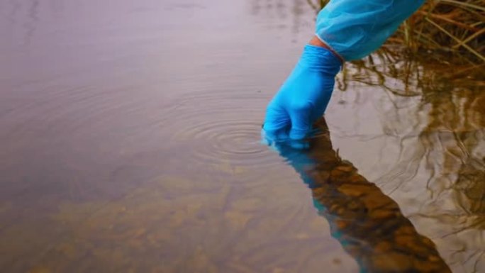 男生物学家检查湖泊中的氧气水平，戴上蓝色手套将水吸入试验瓶，水库水污染的概念，游泳许可