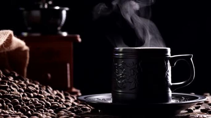。热咖啡杯。特写从陶瓷黑色咖啡杯中提取的美丽的自然热气冒烟，带有深色背景上的老式研磨机浓缩咖啡，4k