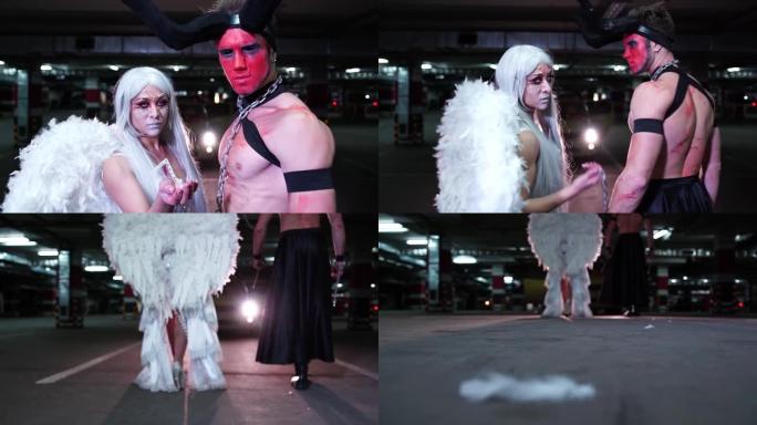 一个穿着魔鬼服装的年轻人在万圣节与一个伪装成天使的怪异女孩在地下停车场