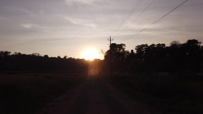4k慢动作的阳光照射在印度卡纳塔克邦绿色田野之间的道路上
