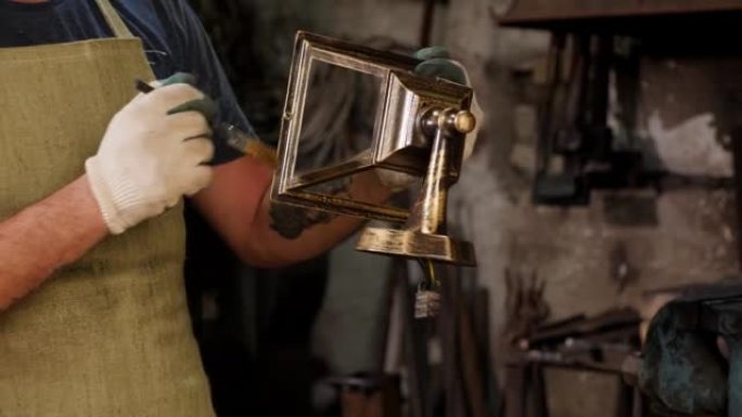 一个铁匠用金粉在锻造中画金属钟的特写镜头。