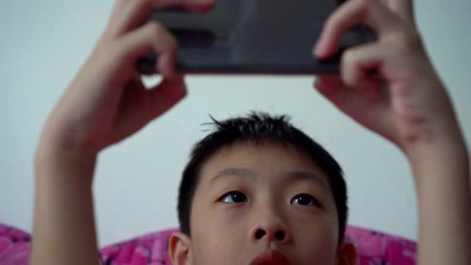 倾斜亚洲小孩玩手机。