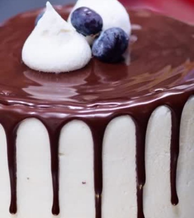 蛋糕设计师用浆果蛋白酥皮巧克力装饰磨砂滴蛋糕顶部