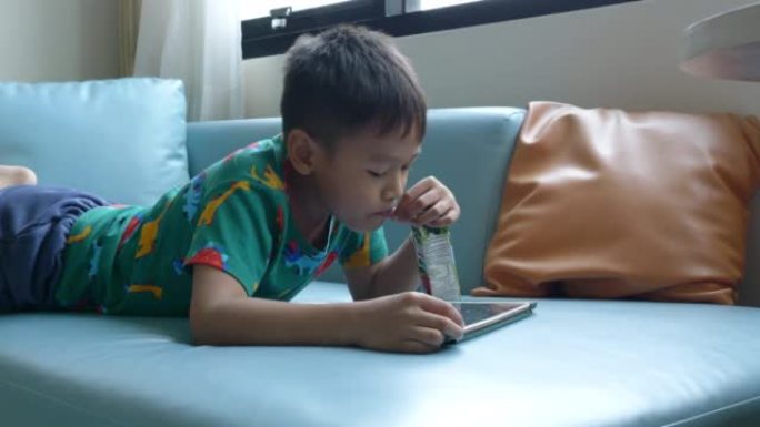 亚洲男孩不由自主地躺在平板电脑上。