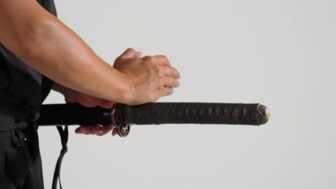 一名日本男子身穿黑色和服，从武士刀鞘中拔出武士刀