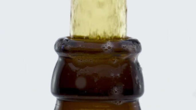 流淡啤酒从瓶颈飞溅在超慢动作特写。