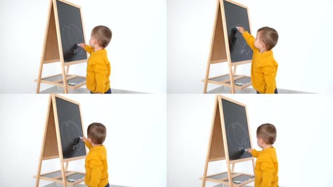 小男孩在黑板上用粉笔画画