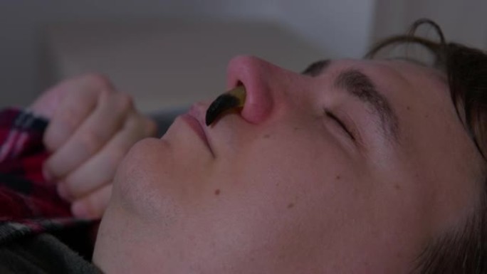 绿色鼻涕虫爬进睡人的鼻孔，侧视，特写。