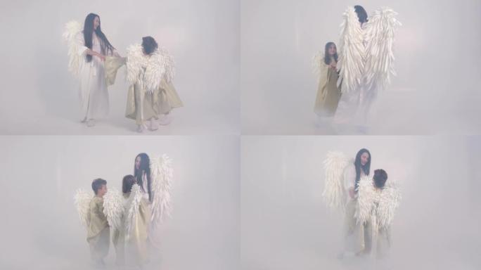 一个迷人的视频，一个母亲带着孩子在烟雾中以天使的形式带着白色的翅膀。4k视频