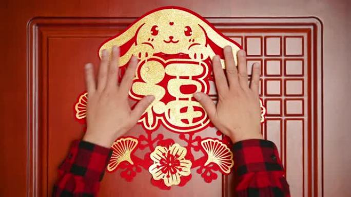 男子将农历新年的兔子装饰贴在横作文的门上中文单词的翻译是财富没有徽标没有商标