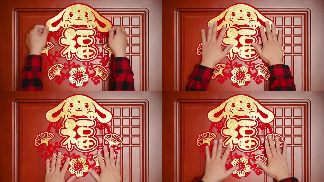 男子将农历新年的兔子装饰贴在横作文的门上中文单词的翻译是财富没有徽标没有商标