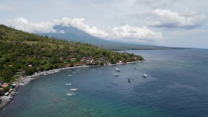 巴厘岛沿海城镇阿梅德海滩的电影鸟瞰图，远处有阿贡山。