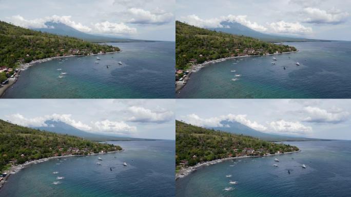 巴厘岛沿海城镇阿梅德海滩的电影鸟瞰图，远处有阿贡山。