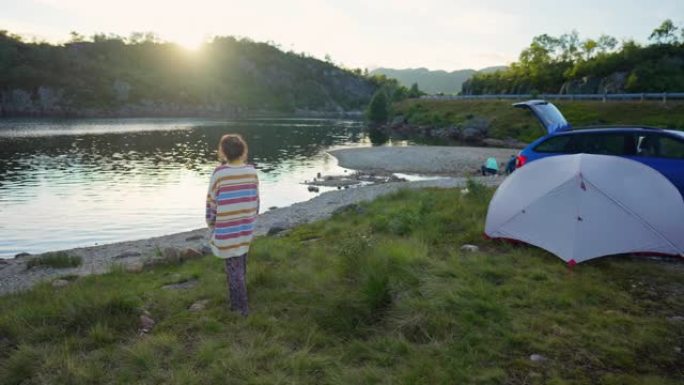 妇女在挪威的帐篷和汽车附近的湖附近行走