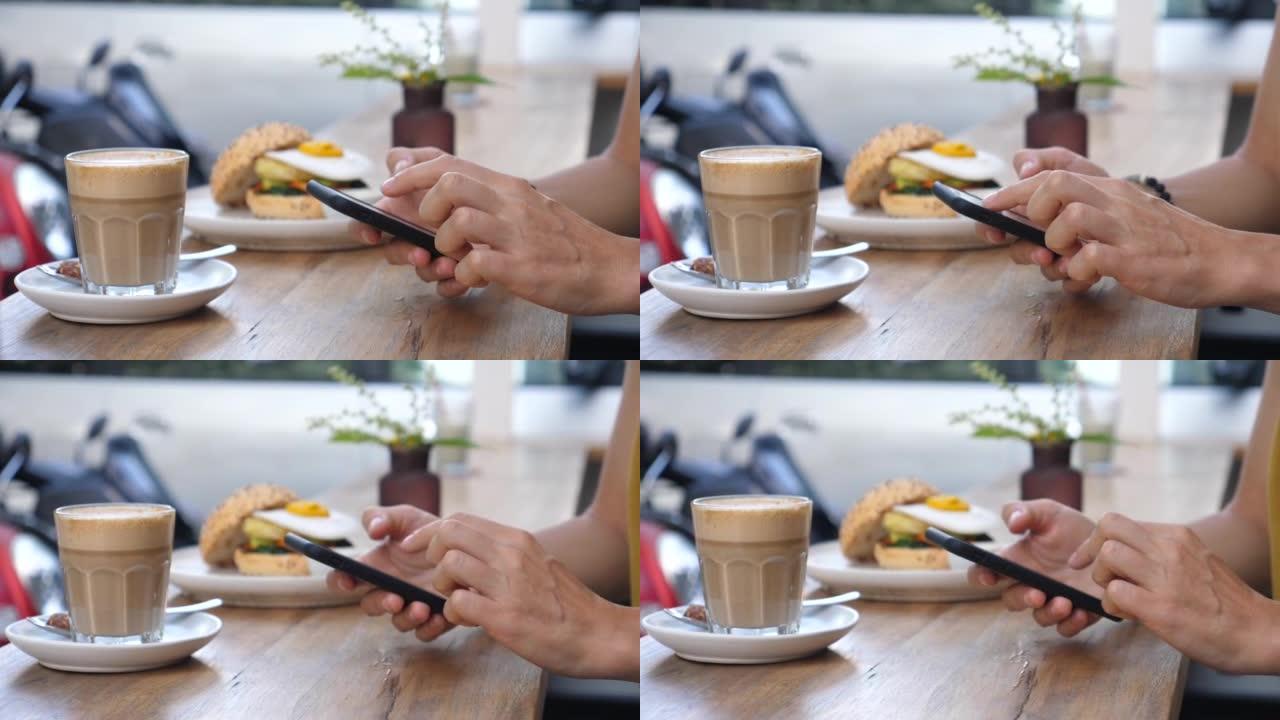 用智能手机拍摄女性双手的特写。一名妇女在吃素汉堡和植物性咖啡午餐的同时，在电话簿中寻找联系人进行直播