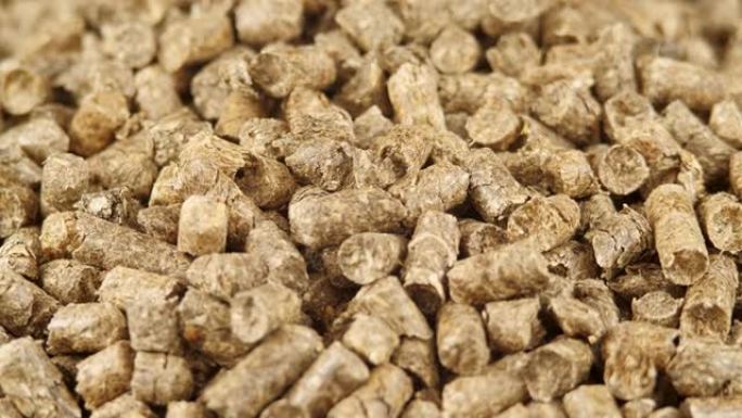 压实秸秆颗粒作为天然猫砂填料或有机燃料的特写旋转。茅草颗粒背景。可再生替代能源。寒冷季节加热材料