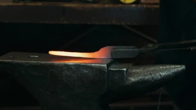 一位钢铁大师撞击高热金属并对其进行整形的特写镜头