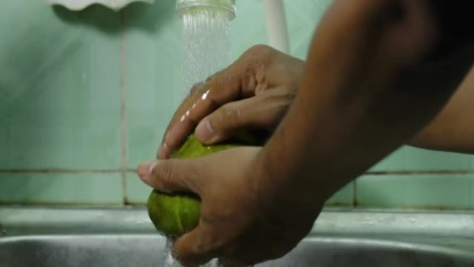 关闭男子手洗Manalagi型芒果水果在自来水在家
