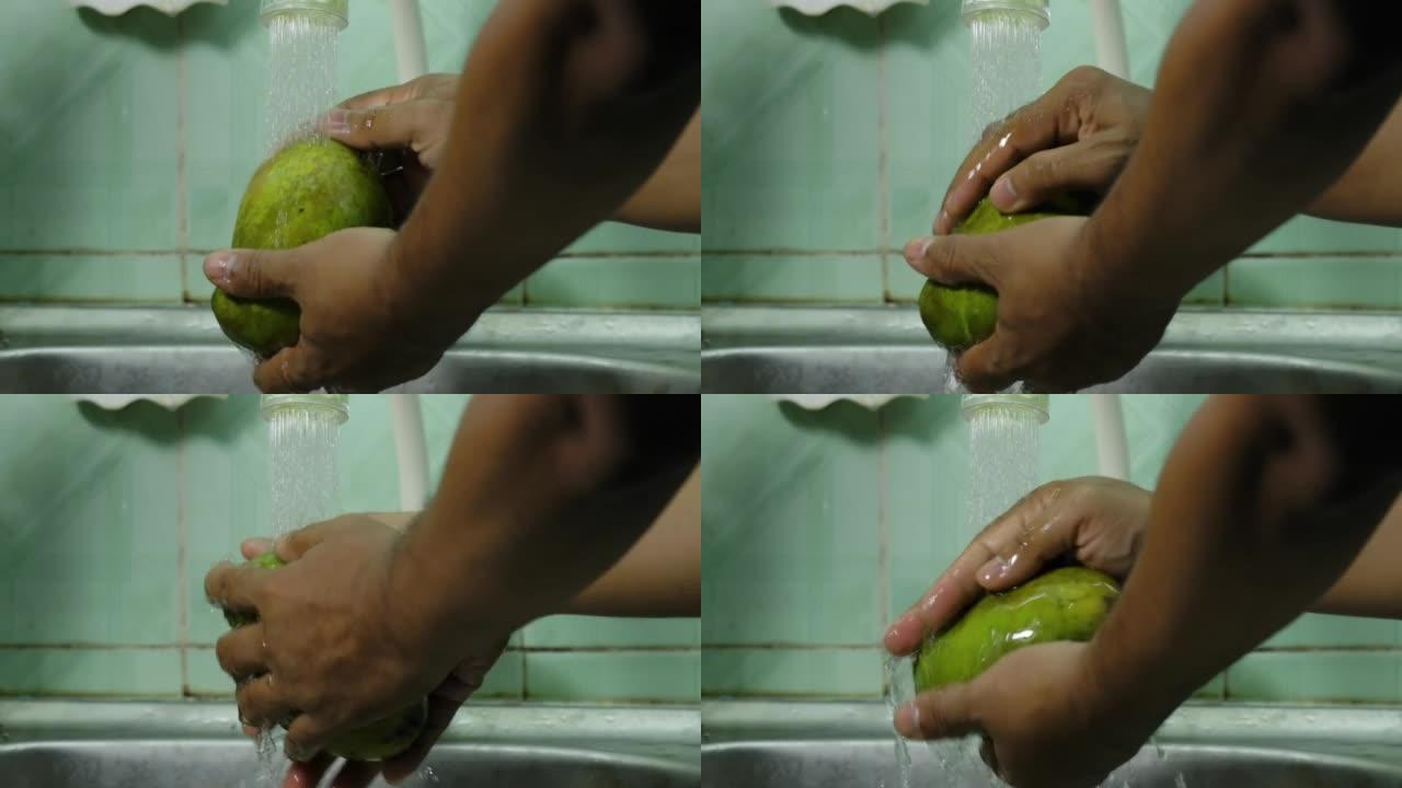 关闭男子手洗Manalagi型芒果水果在自来水在家