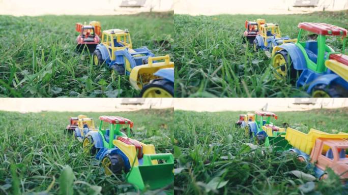儿童玩具 -- 拖拉机和汽车在草地上一字排开。