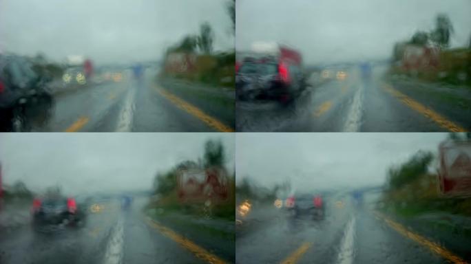 在雨中，在阴沉的天气里，在高速公路上行驶。高速公路上的超车被雨水模糊了。雨刮器擦拭汽车雨水浸湿的挡风